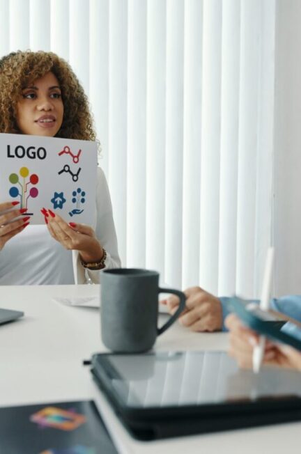 Entrepreneur comparant son logo avec celui d’un concurrent sur deux documents imprimés.