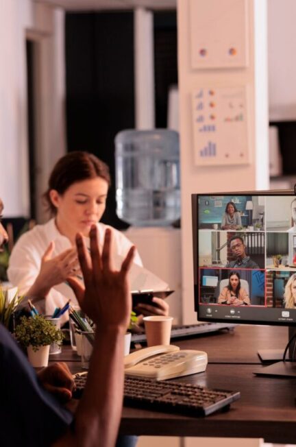 Équipe en télétravail réunie en visioconférence autour d’un tableau de suivi des objectifs.