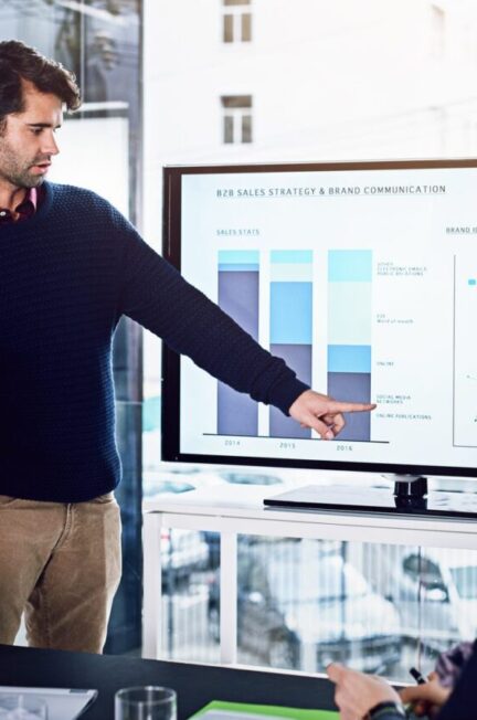 Ingénieur présentant un tableau de bord technique à une équipe en réunion.
